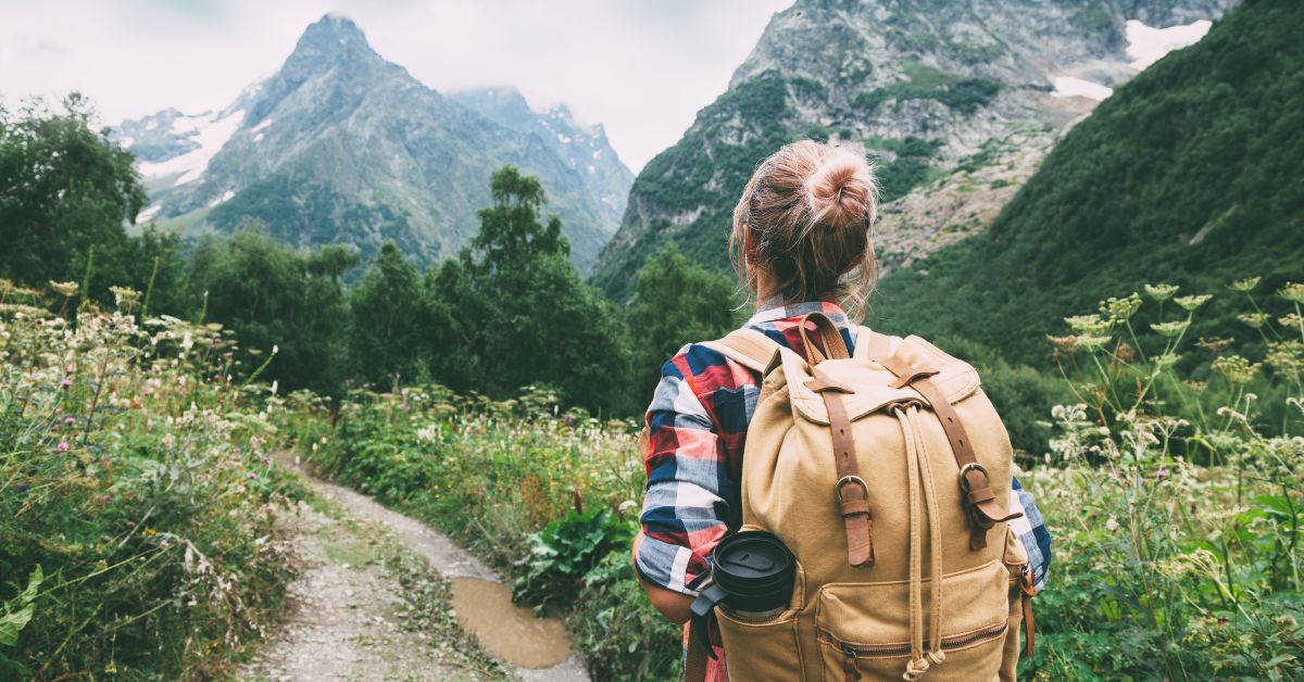 Outdoor adventurer hiking with backpack through mountain landscape.